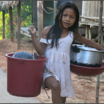 APRENDER HACIENDO. Niña matsés regresa a su casa, después de ayudar a su familia, ocupándose de lavar platos y olla en el río. [imagen 1]